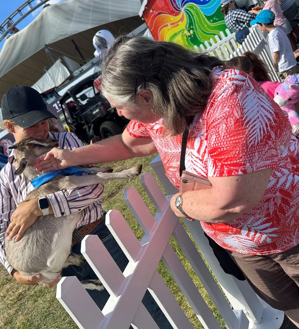 A client patting a goat at the show during a supported community outing