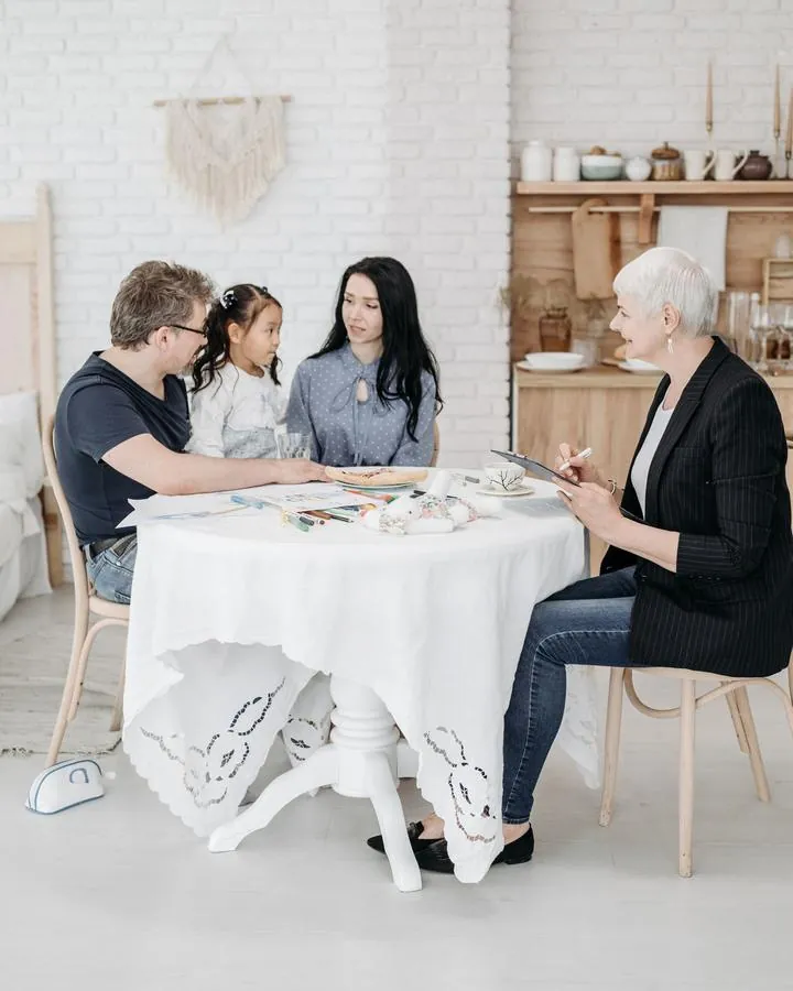 A support coordinator chatting with a family around a table in a bright room