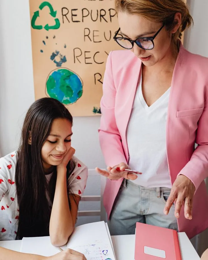 A teacher helping a high-school student with her work
