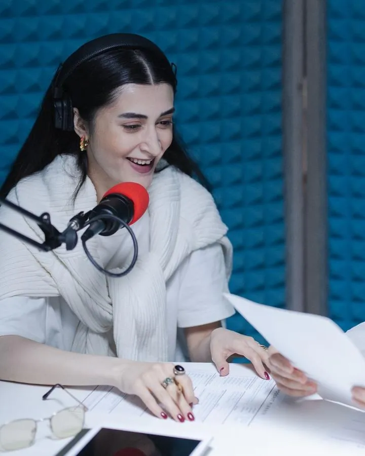 A young woman speaking into a microphone in a recording studio