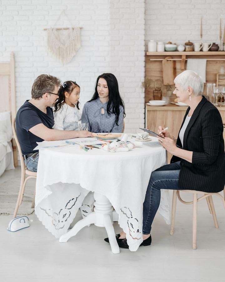A support coordinator chatting with a family around a table in a bright room