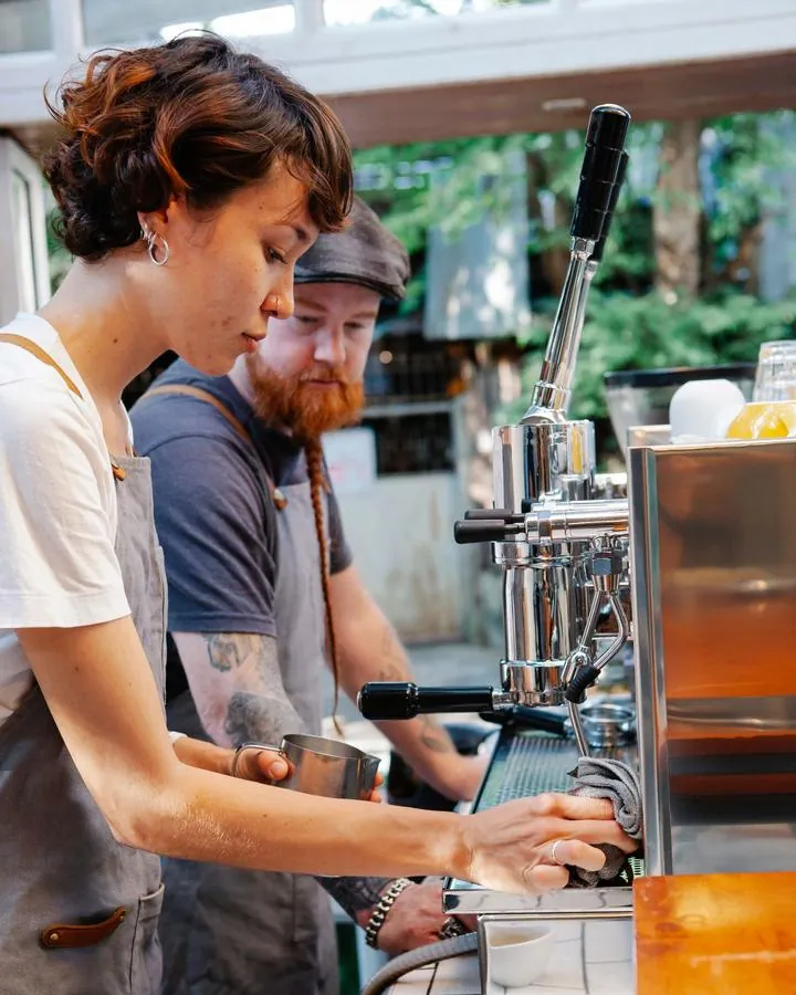 Two baristas working side by side at an espresso machine