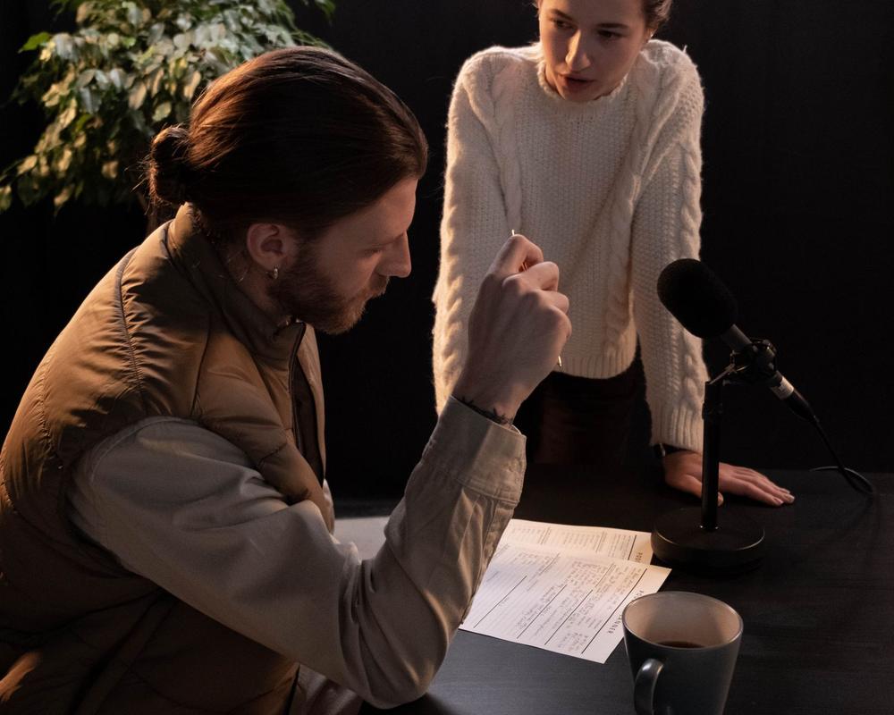 Two people planning a segment at a studio table with a microphone