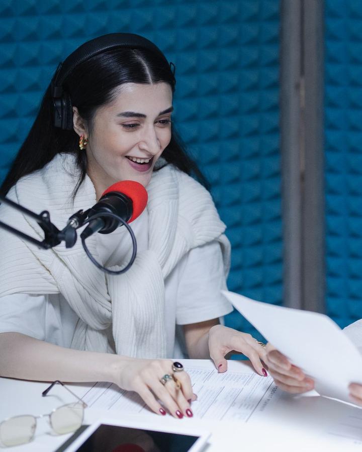 A young woman speaking into a microphone in a recording studio